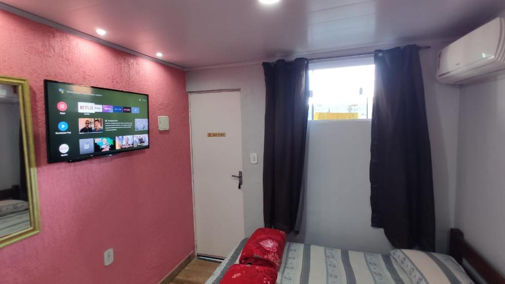 a room with a bed and a tv on a wall at Space Hostel , quartos privativos in Arraial do Cabo