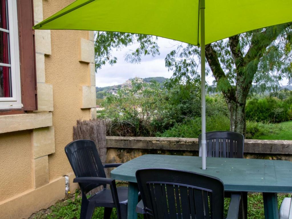 una mesa verde con 2 sillas y una sombrilla en Gîte Castelnaud-la-Chapelle, 3 pièces, 4 personnes - FR-1-616-240, en Castelnaud La Chapelle