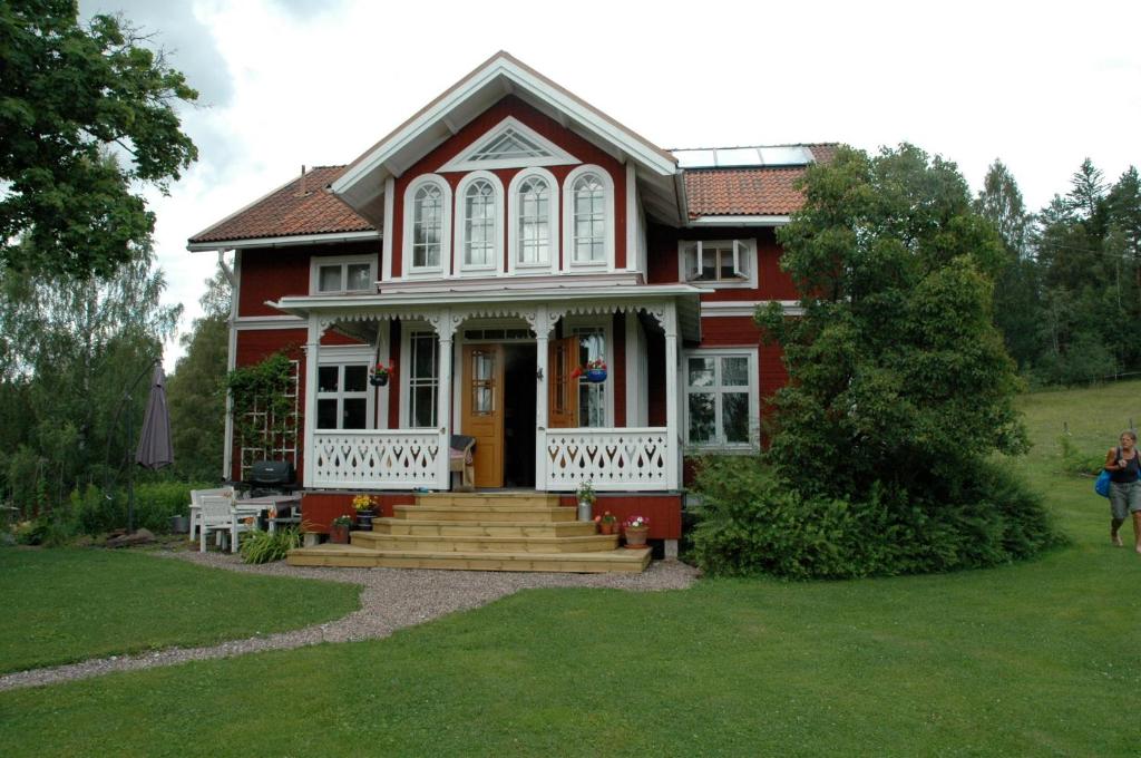 une maison rouge avec une terrasse couverte à l'avant et des escaliers dans l'établissement Wiborggården Bed and Breakfast, à Boda