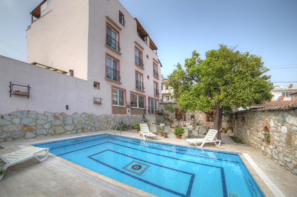 a swimming pool with two chairs and a building at Nazar Hotel in Selcuk