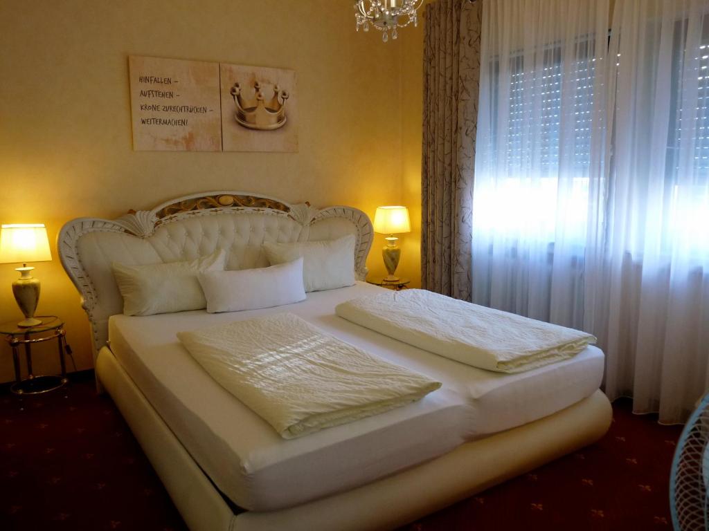 a bedroom with a white bed with two pillows at Hotel Geissler in Stuttgart