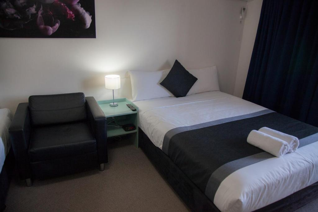 una habitación de hotel con 2 camas y una silla en Chermside Court Motel, en Brisbane