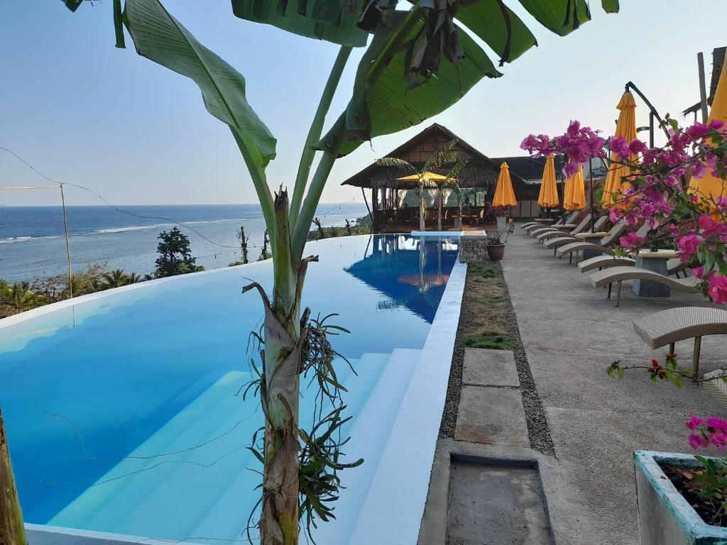 une piscine dans un complexe avec l'océan en arrière-plan dans l'établissement Miley Lodging Restobar, à New Busuanga