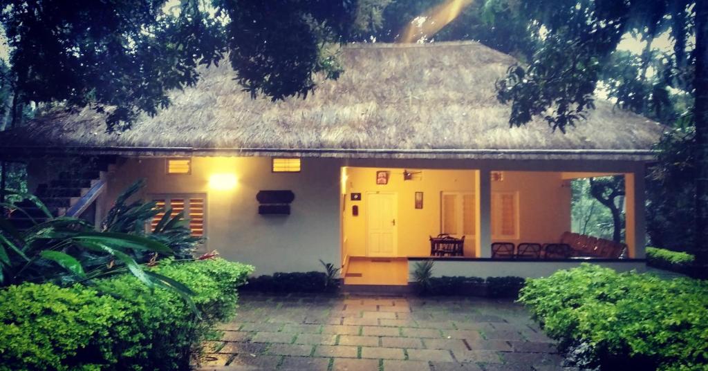 mały biały dom z dachem krytym strzechą w obiekcie Davis Farm House w mieście Maraiyūr