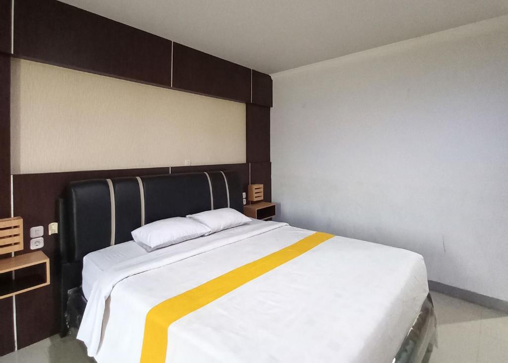 a bedroom with a large bed with a yellow stripe on it at RedDoorz near Poso City Mall in Poso