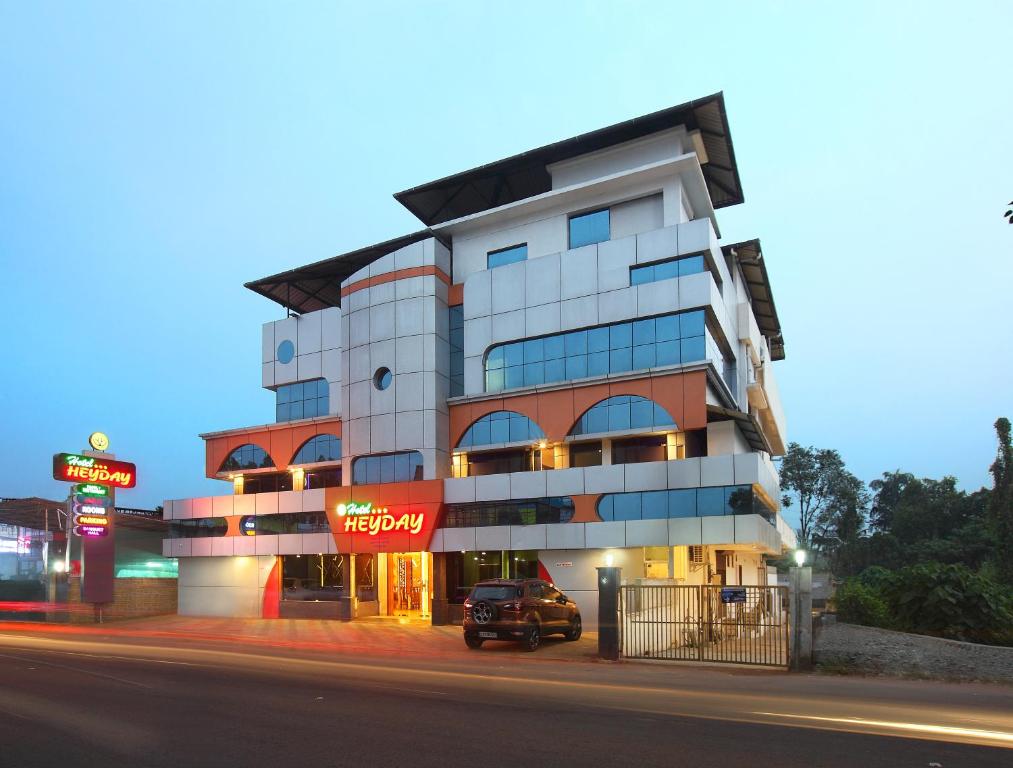 a building with a car parked in front of it at Hotel Heyday in Pathanāmthitta