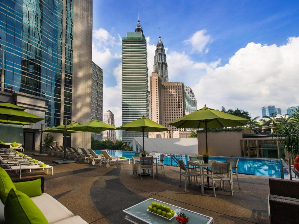 a rooftop patio with tables and umbrellas and a city skyline at Impiana KLCC Hotel in Kuala Lumpur