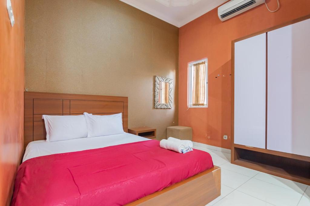 Hotel Markoni Pamanukan Mitra RedDoorz في Pamanukan-hilir: غرفة نوم بسرير كبير مع بطانية حمراء