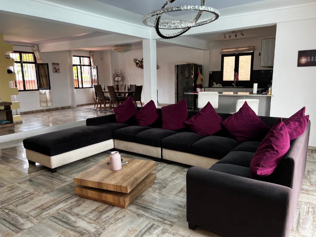 sala de estar con sofá negro y almohadas moradas en Villa Annjo en Pointe aux Piments