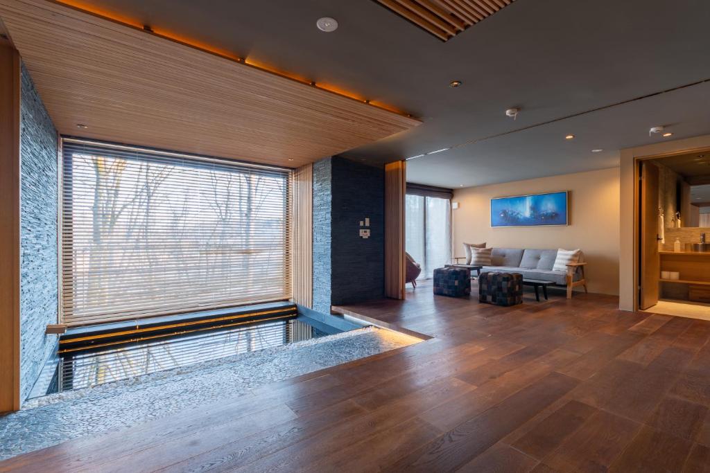 uma sala de estar com uma grande janela e um sofá em Hideaway on Escarpment by H2 Life em Niseko