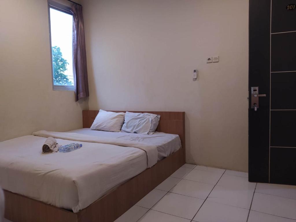 2 Betten in einem kleinen Zimmer mit Fenster in der Unterkunft RedDoorz At Kartini Residence Semarang in Semarang