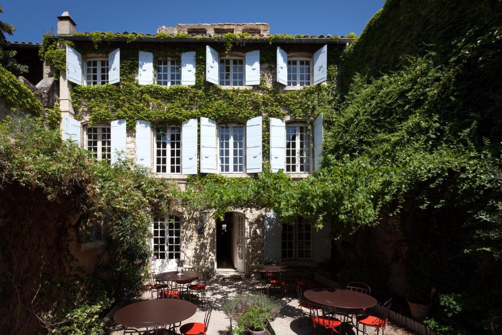 un edificio con mesas y sillas delante de él en Hotel De L'Atelier en Villeneuve-lès-Avignon