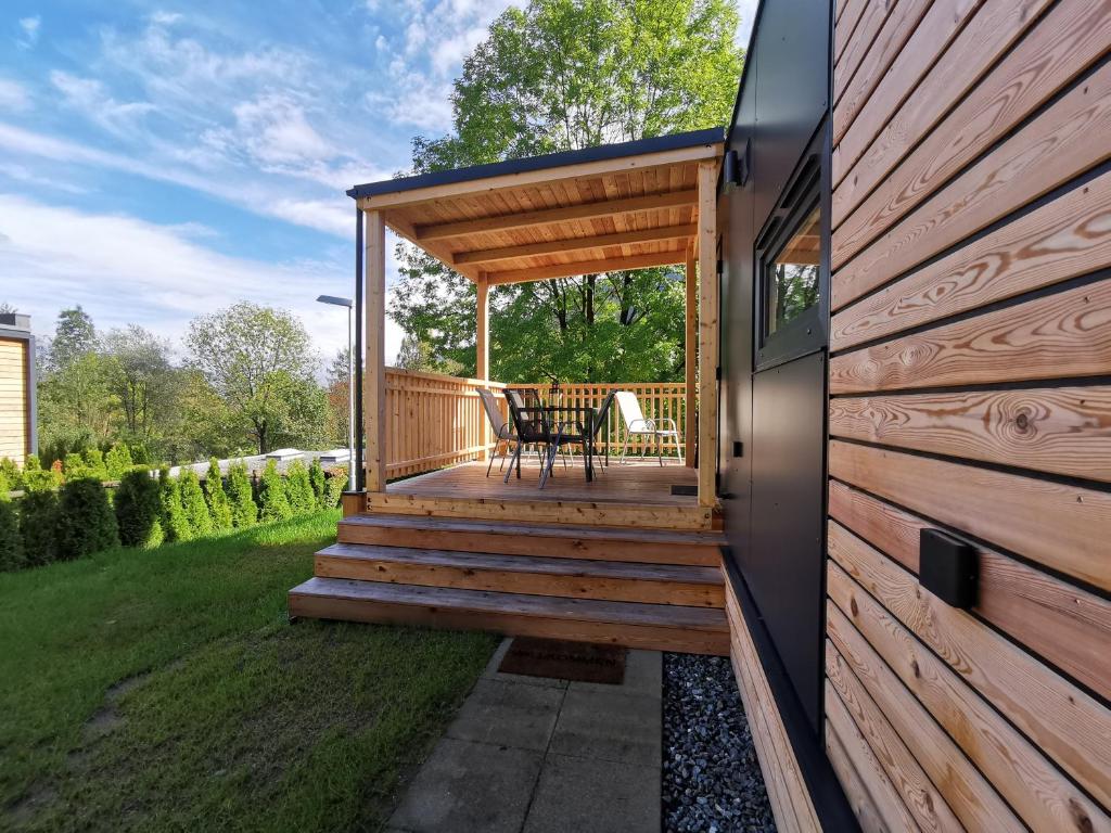 a wooden house with a deck with a table at Seecamping Berghof - Mobilheime in Landskron