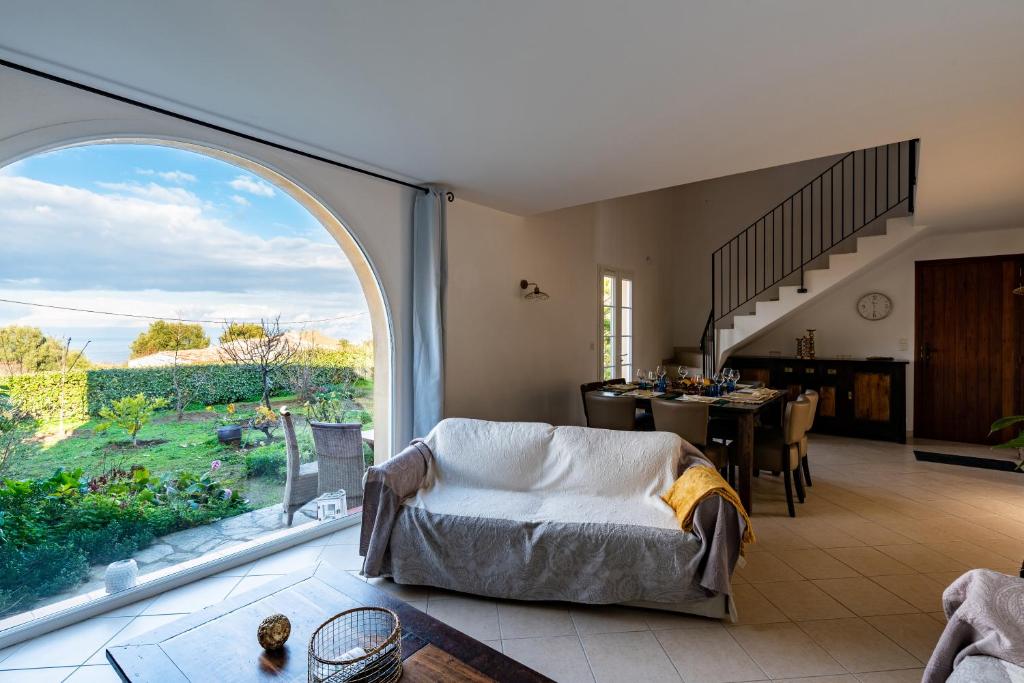 ein Wohnzimmer mit einem großen Fenster und einem Tisch in der Unterkunft Aria - Vue Mer in Aregno