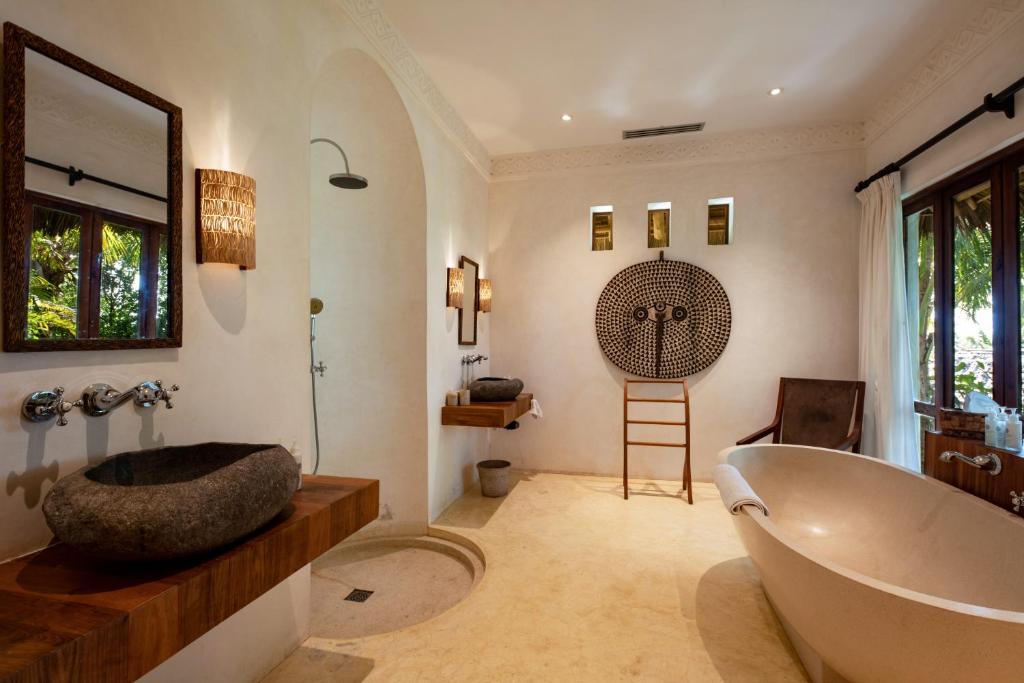 a bathroom with a large tub and a sink at Qambani Luxury Resort in Michamvi