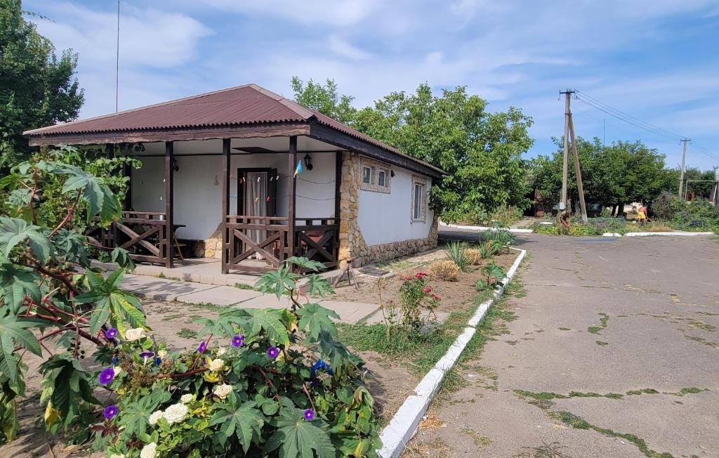 um pequeno edifício com um alpendre e algumas flores em Київська Чайка Коблево em Sychavka
