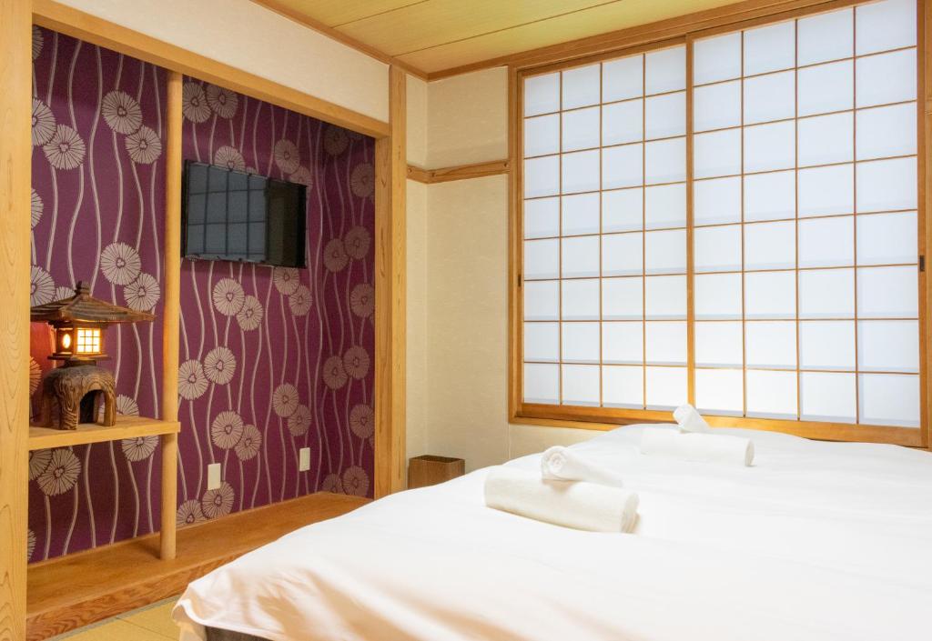 a bedroom with a white bed and a window at T Square Hakuba in Otari