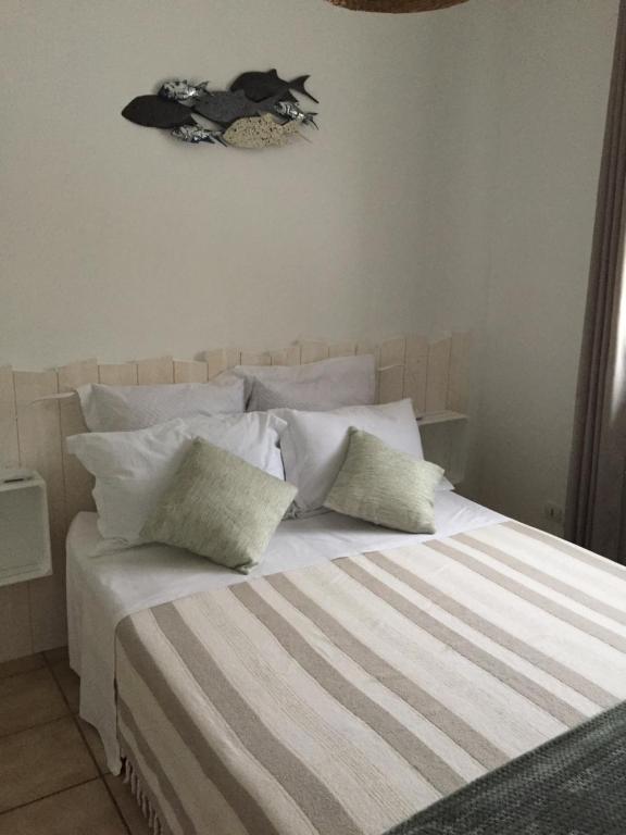 un letto con lenzuola e cuscini bianchi in una camera da letto di LES HIPPOCAMPES a La Teste-de-Buch