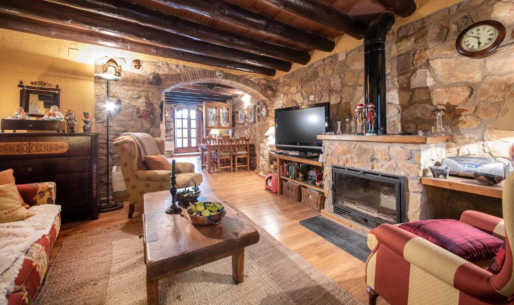 a living room with a stone fireplace and a tv at Casa La morera del Montsant in La Morera de Montsant