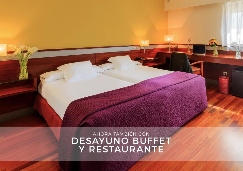 a hotel room with a bed with a purple blanket at Hostal Torrejón in Torrejón de Ardoz