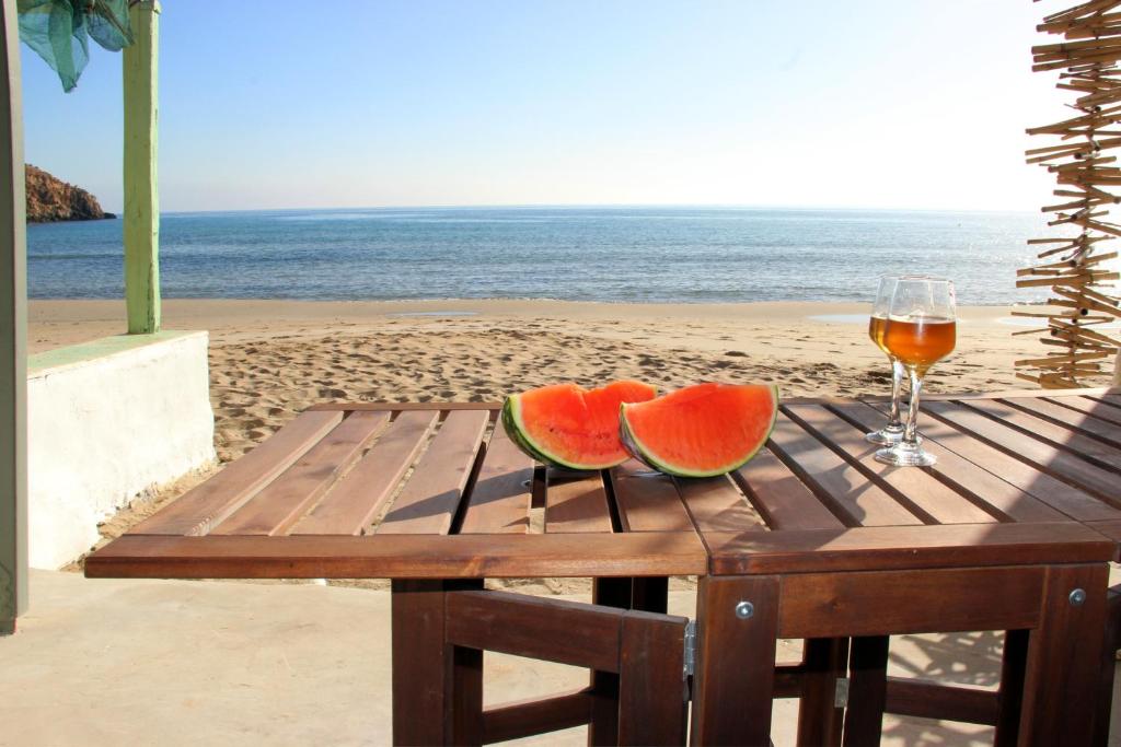 une table en bois avec deux tranches de pastèque sur une plage dans l'établissement Manis Sirma (fisherman's house by the Sea), à Provatas