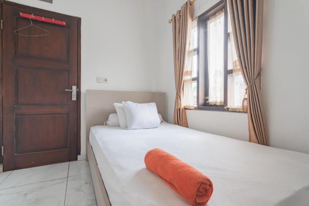 een slaapkamer met een bed met een oranje handdoek erop bij Small Homestay Syariah Sikembar Ciwidey Mitra RedDoorz in Bandung
