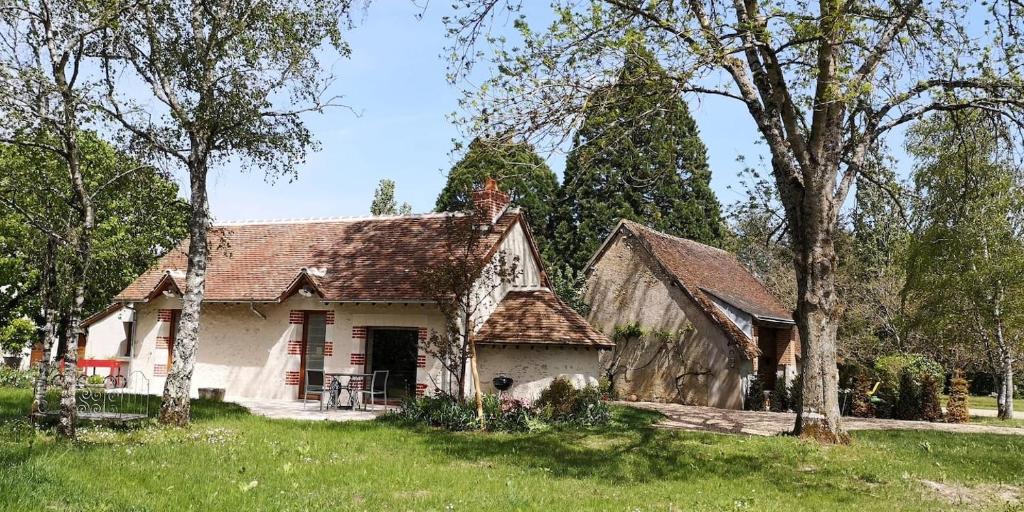 uma casa branca com um telhado castanho e algumas árvores em Le Petit Pavillon em Cheverny