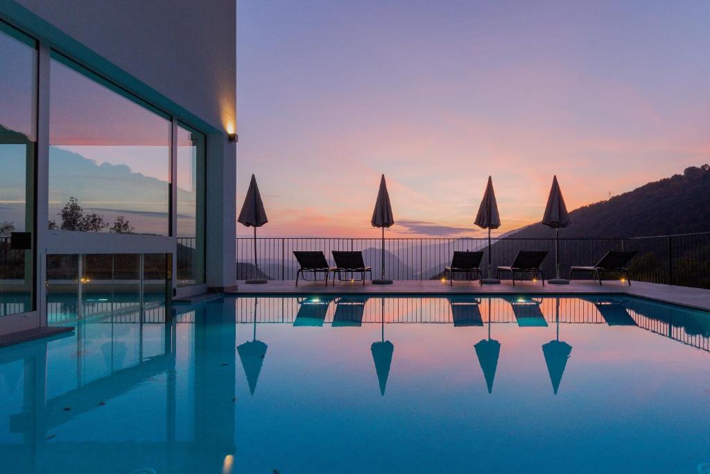 a swimming pool with chairs and a sunset in the background at Il Bagnolo Eco Lodge in Salò