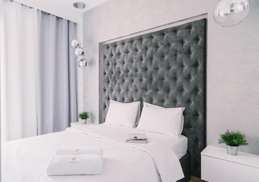 a bedroom with a large white bed with a black headboard at Apartment4You Select Kolejowa in Warsaw
