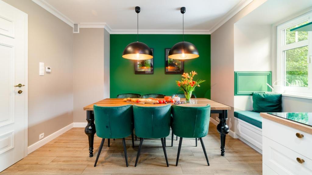 une salle à manger avec des murs verts et une table avec des chaises vertes dans l'établissement Royal Green - Apartamenty Deptak, à Karpacz