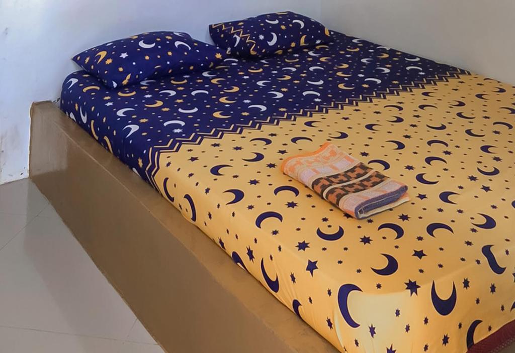 a bed with polka dot sheets and a comforter at Pondok Sundawa 2 Pangandaran Mitra RedDoorz in Pangandaran