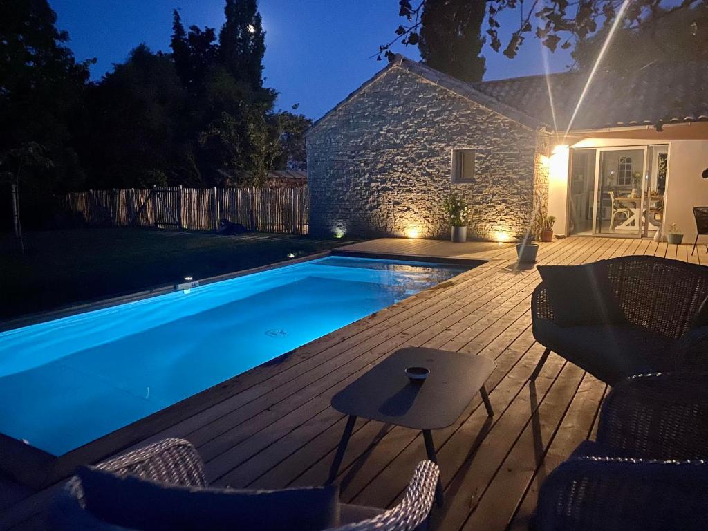 a swimming pool with chairs on a wooden deck at La belle étoile chambres d'hôtes in Saint-Jean-de-Monts