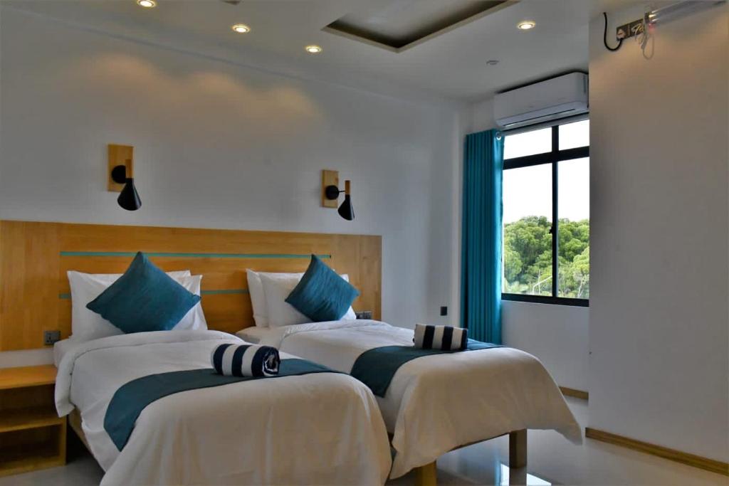 2 camas en una habitación con ventana en Wish Guesthouse, en Huraa