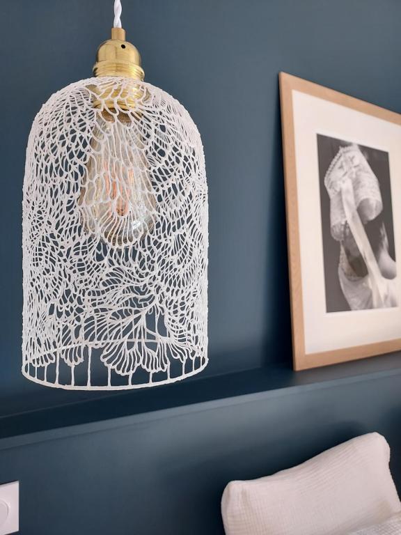 a lamp with a white cage hanging from a wall at Maison Triton et Porcelaine in Saint-Coulomb