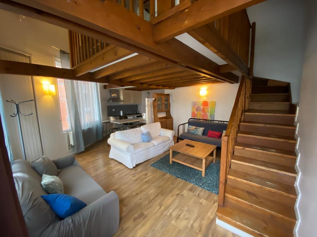 a living room with a couch and a staircase at De Disney à Paris appartement avec parkings gratuits et sécurisés, au pied des transports in Nogent-sur-Marne