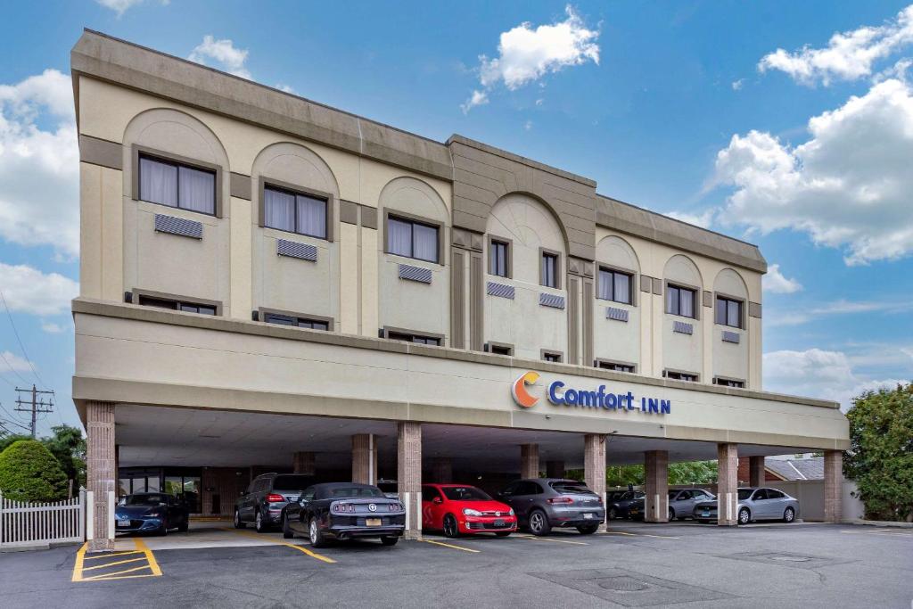 ein Gebäude mit Autos auf einem Parkplatz in der Unterkunft Comfort Inn Syosset-Long Island in Syosset