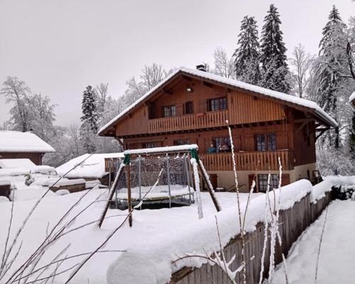 uma casa coberta de neve com um baloiço em Chalet Esprit em Morillon