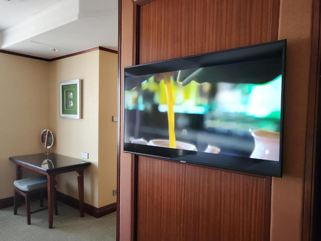 A compact in-room vanity and desk beside a wall-mounted television.