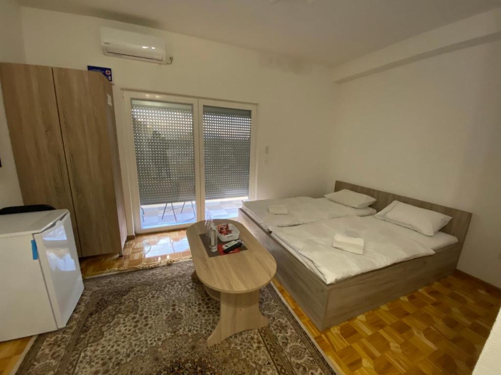 Kleines Zimmer mit einem Bett und einem Tisch in der Unterkunft Apartmani Hadžić in Živinice