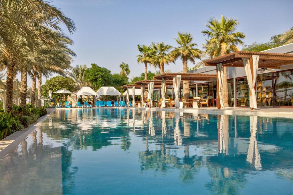 a swimming pool with palm trees and a resort at Meliá Desert Palm Member of Meliá Collection in Dubai