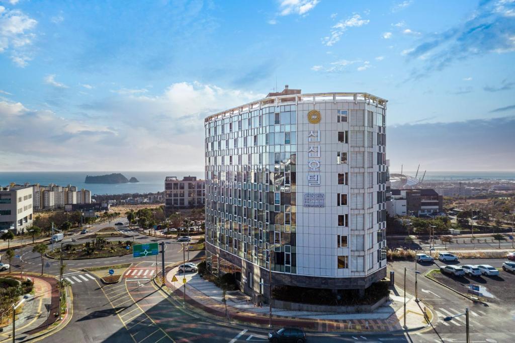 a tall white building in front of a city at Shin Shin Hotel Jeju Worldcup in Seogwipo