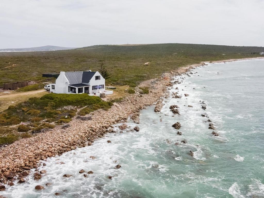 a house on the shore of a body of water at Kanon Private Nature Reserve in Mossel Bay