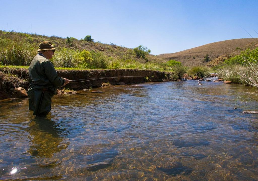 a man standing in a river holding a fishing rod at Highland Run Fly Fishing Estate by Dream Resorts in Lydenburg