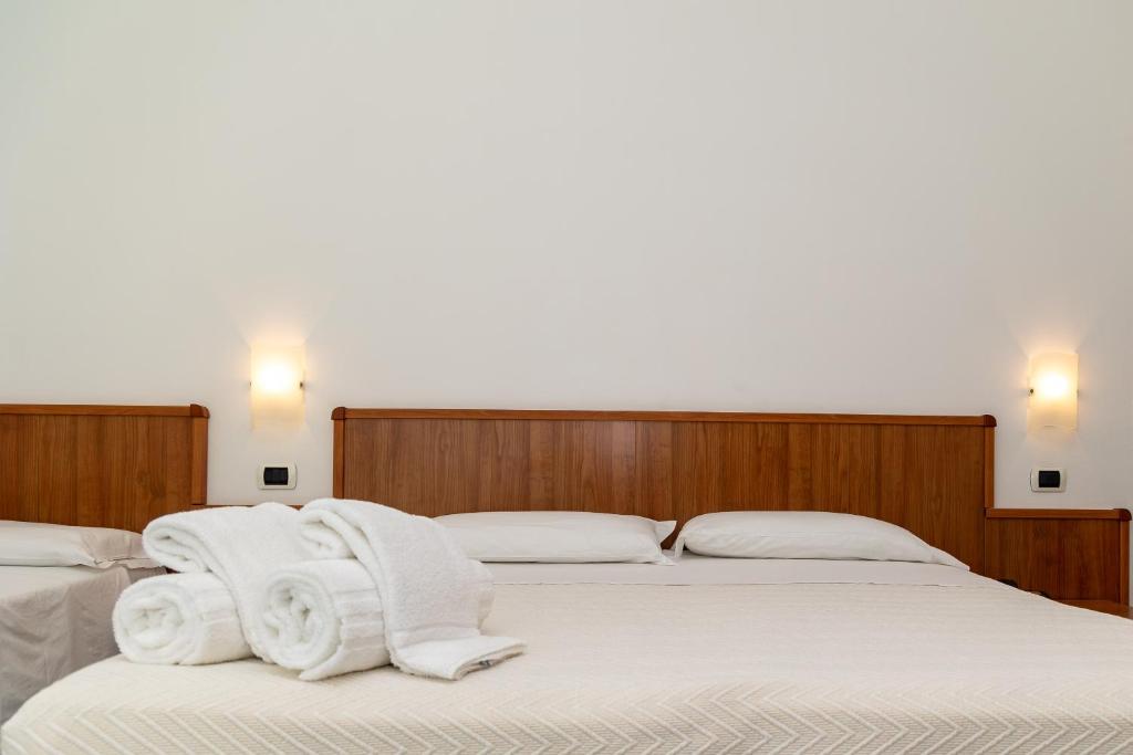 two beds in a room with white towels on them at Hotel Royal in Giulianova