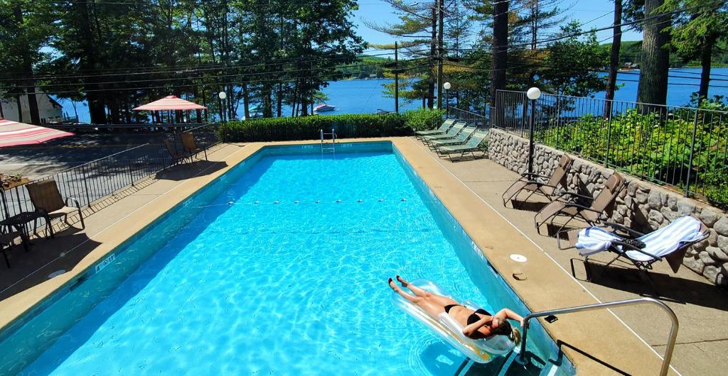 a person laying in a chair in a swimming pool at Birch Knoll Motel in Laconia