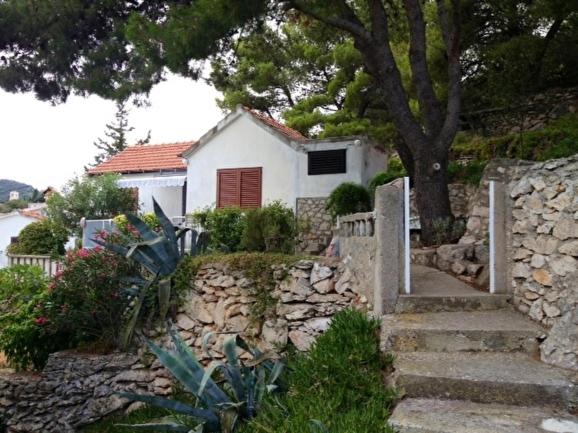 a white house with a tree and a stone wall at Holiday home in Sali with sea view, terrace 4420-1 in Sali