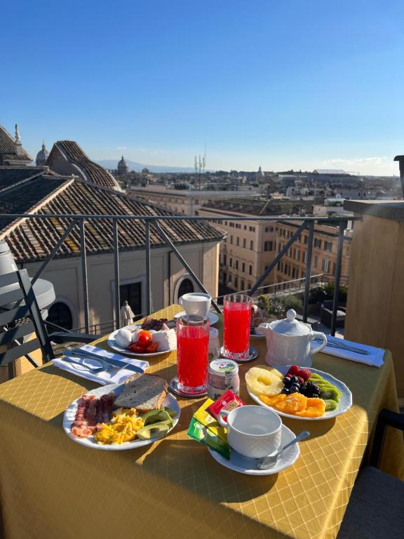 una mesa con platos de comida y bebida en el balcón en Navona Queen Rooftop en Roma