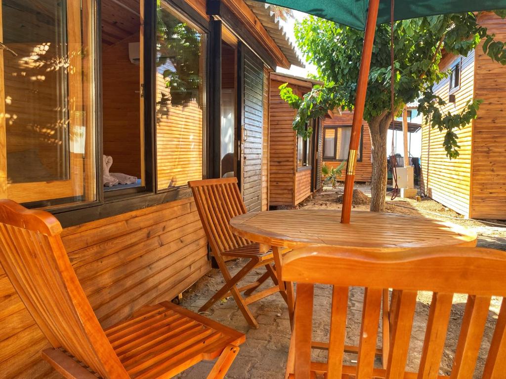 una mesa y sillas en un porche con sombrilla en Lazoğlu Bungalov, en Güzelçamlı