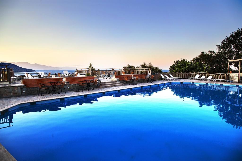 una gran piscina azul con mesas y sillas en Elpida Village, en Istron