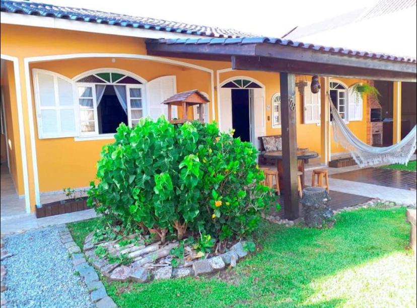 uma casa amarela com uma rede em frente em Ótima Casa para 10 pessoas /menos de 100m da Praia em Florianópolis